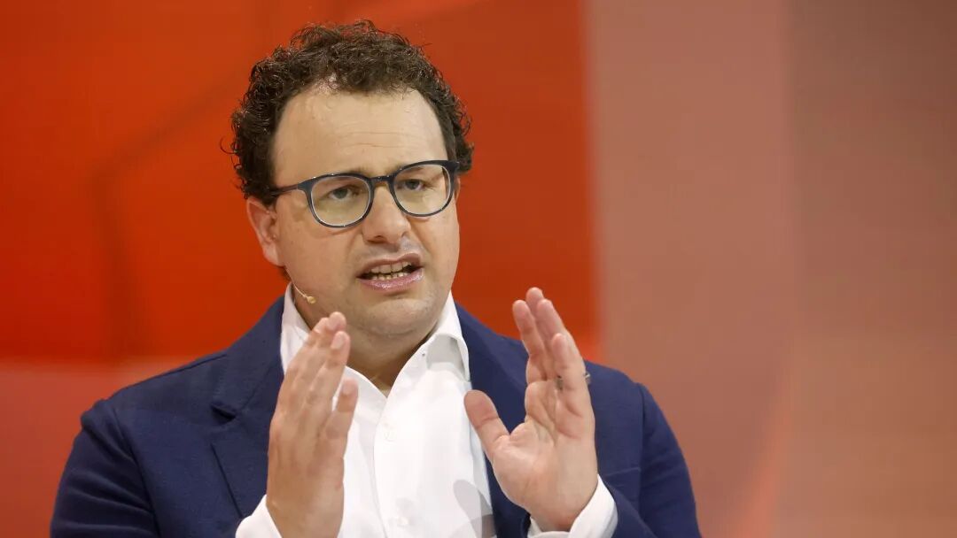 Anthropic CEO Dario Amodei, seated on a stage and gesturing with both hands raised.